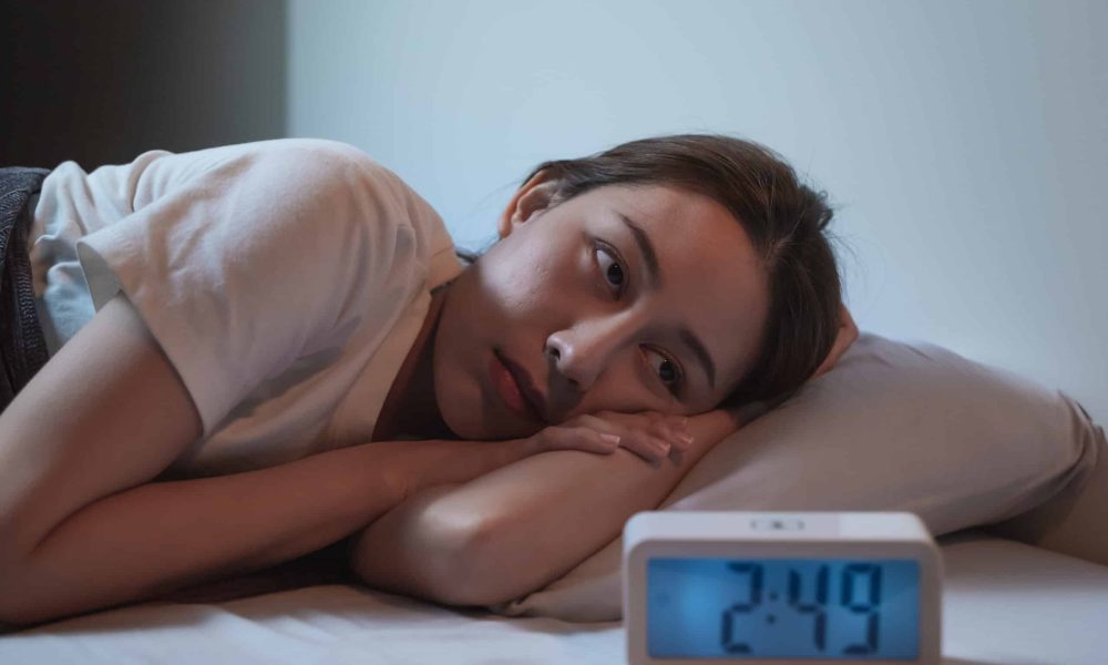 Asian women opened eyes lying on the bed have an insomnia problems.